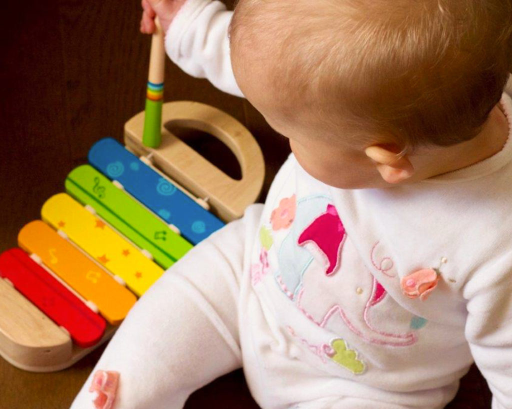 happy baby playing with a toy xylophone
