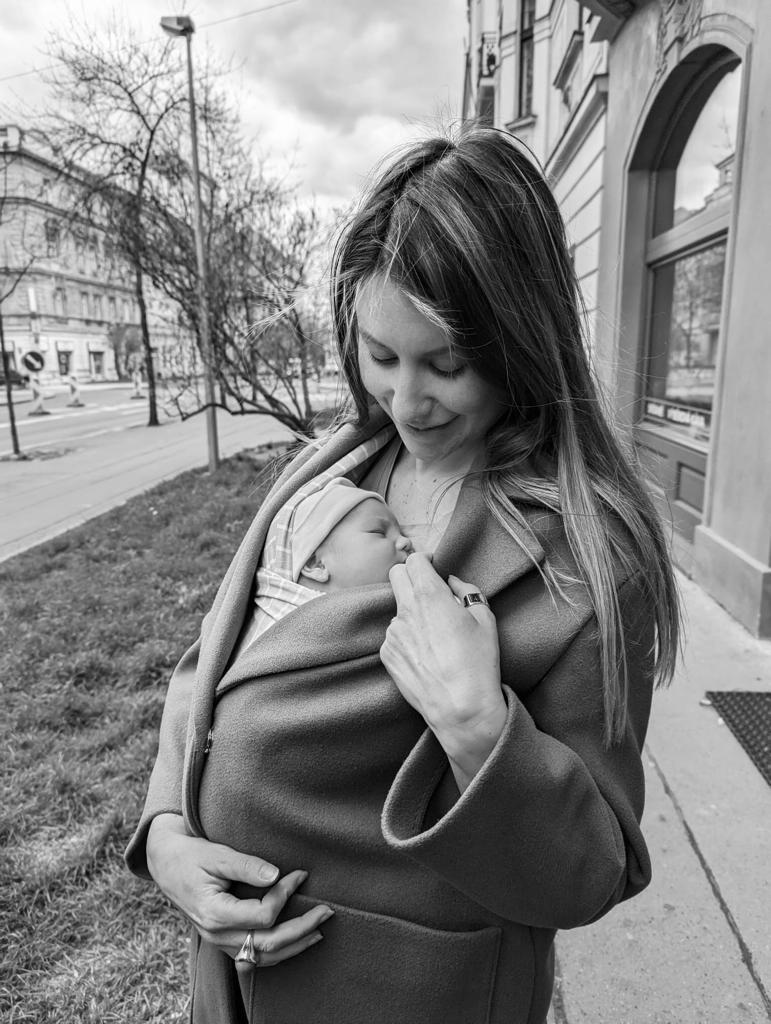 Client Grace holding her newborn Elio in a baby carrier